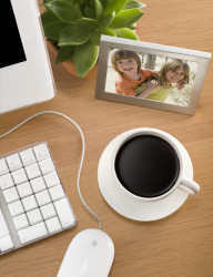 Cup of coffee next to a keyboard and photo of children