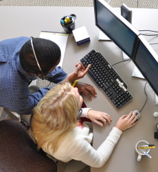 Customer service manager helping an associate with a problem on the computer