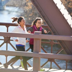 Two women running over a bridge