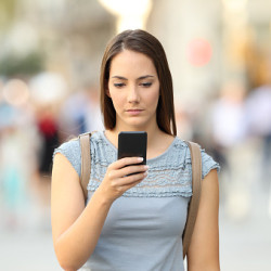 Serious girl checking phone message on the street