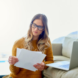 Shot of an attractive young woman reading paperwork while working at home