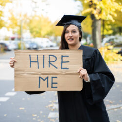 Graduate Student Standing With Hire Me Placard